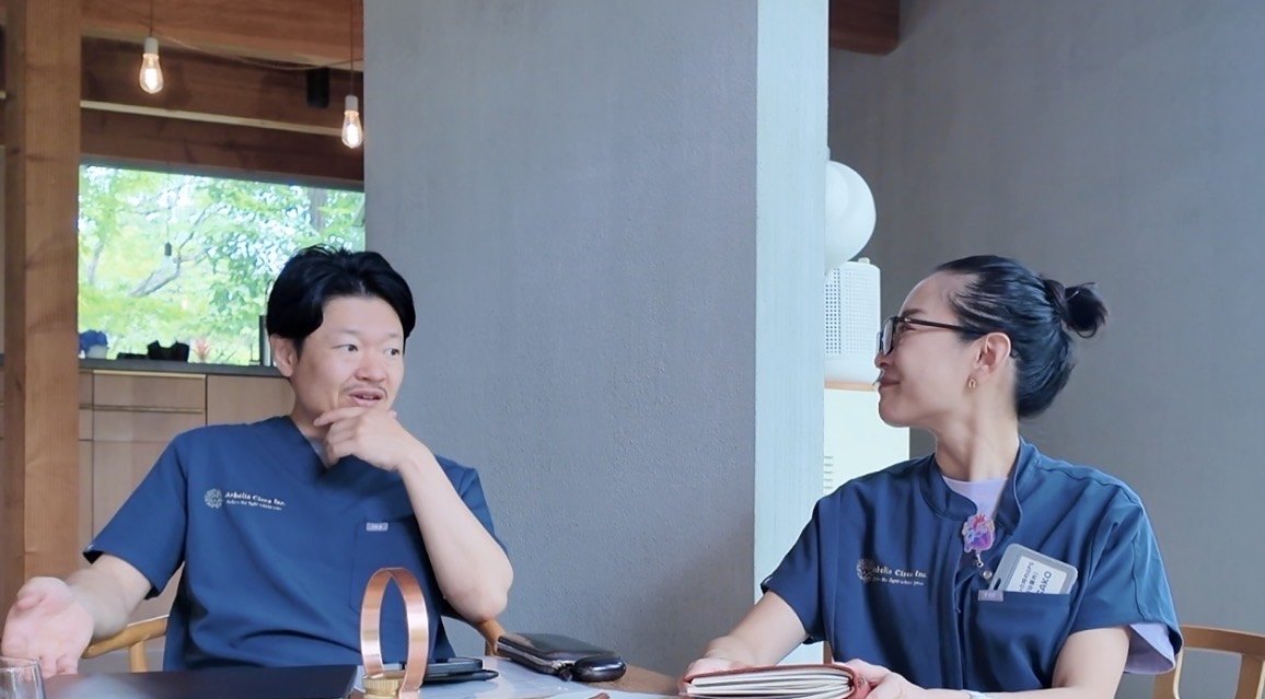 テーブルを挟んで話すHIROKIとASAKO。HIROKIが左、ASAKOが右。